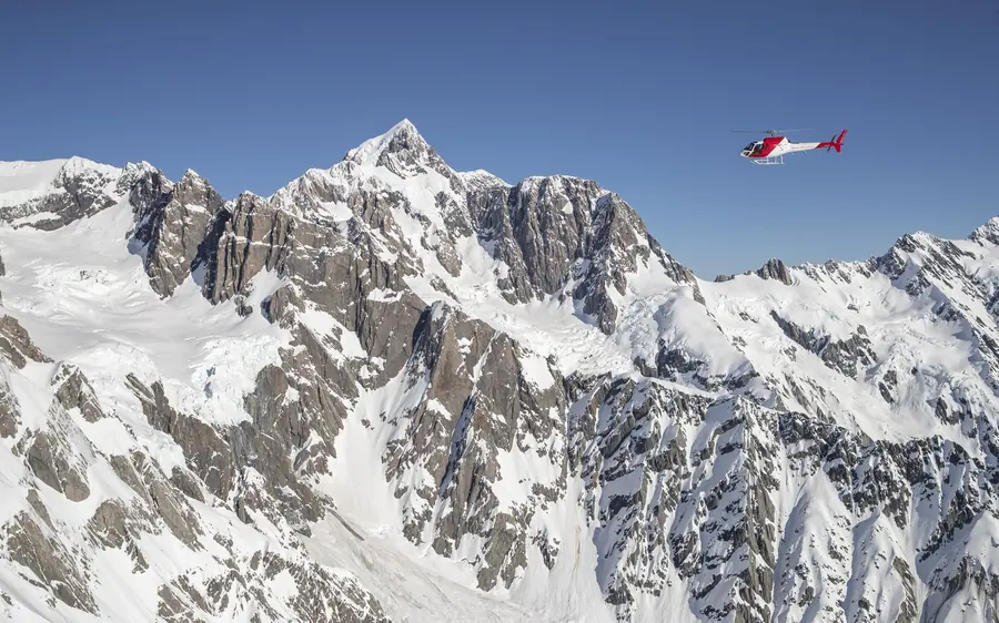 A helicopter flying above the crevasses of the Tasman Glacier